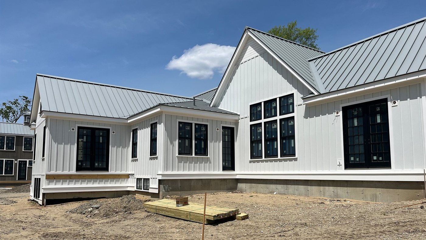 The property during construction, with bare dirt and fill around the finished house.