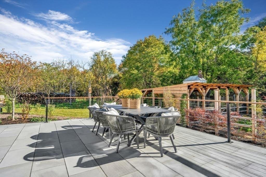 A terrace with a dining set and a pergola behind it.